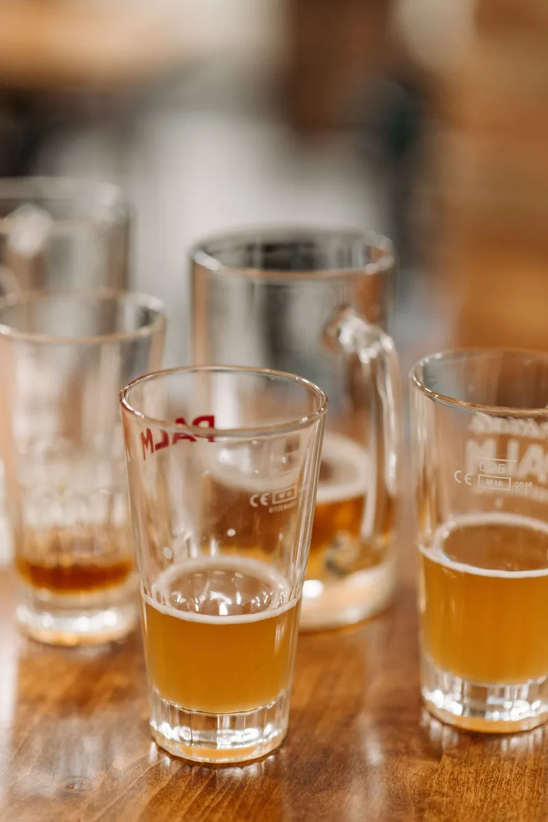 Dos vasos de cerveza a medio beber sobre una mesa de madera en un ambiente informal