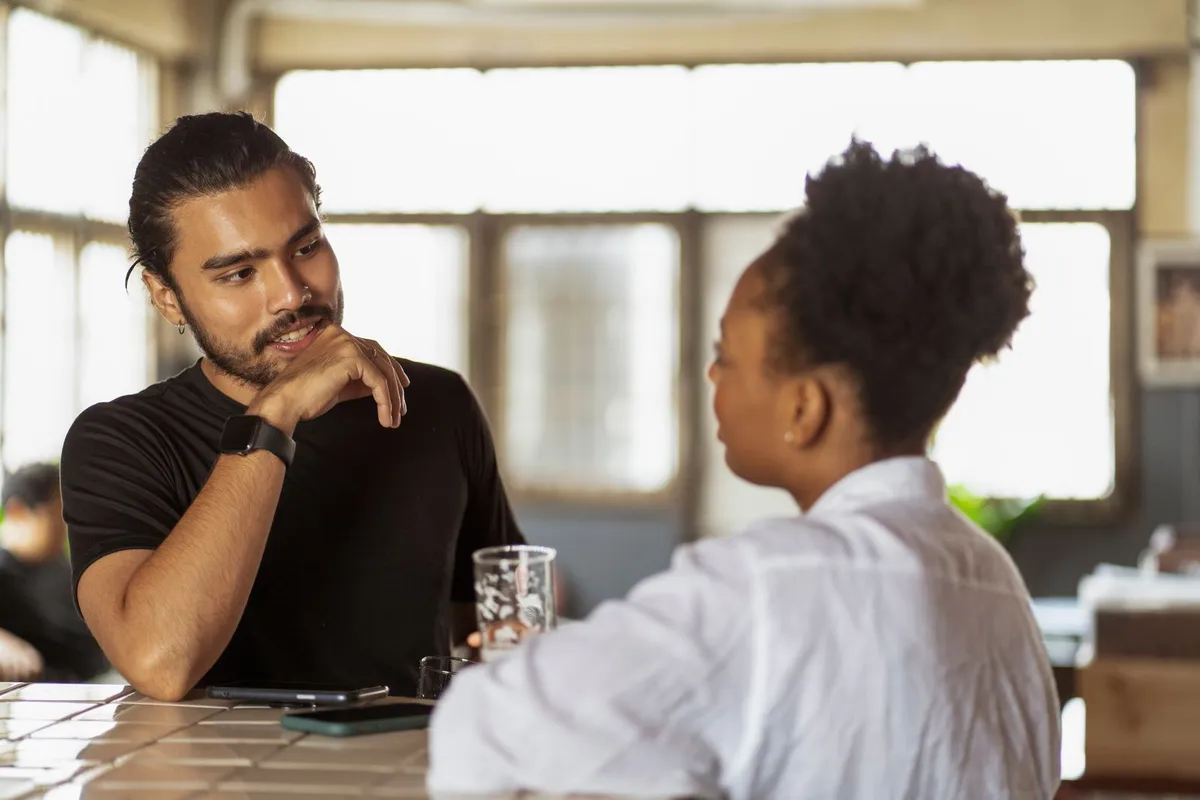 Un hombre y una mujer conversando e intercambiando opiniones en interior