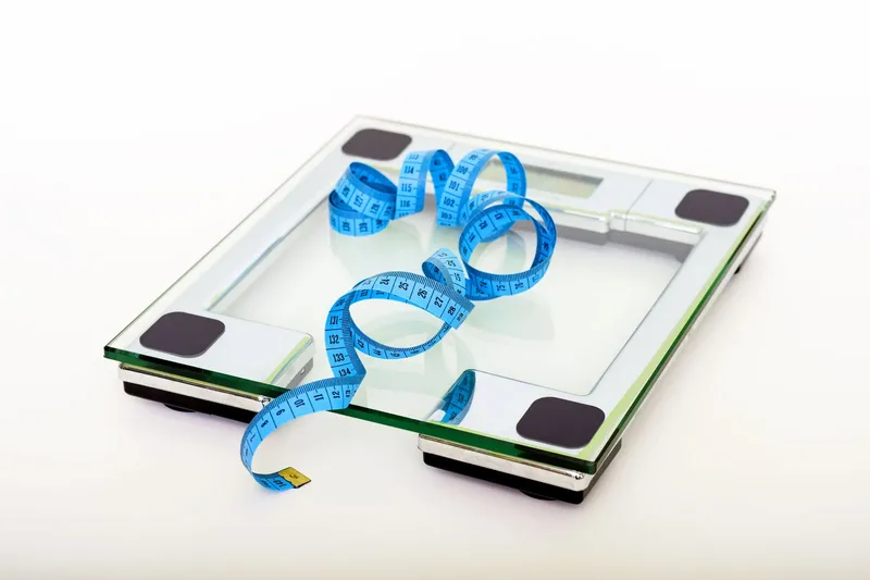 Báscula digital de cristal con una cinta métrica azul para el control del peso.
