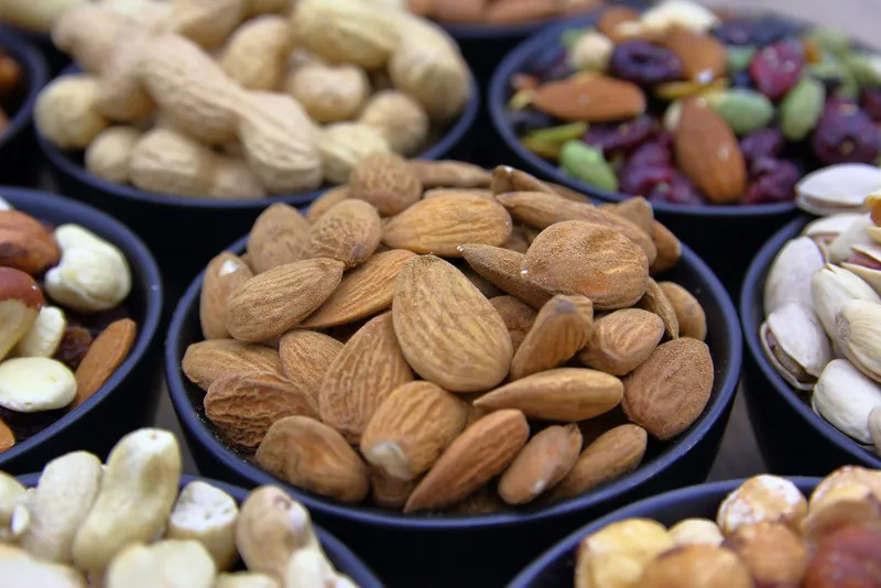 Surtido de frutos secos en cuencos negros como snack keto bajo en carbohidratos
