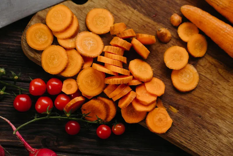 Zanahorias en rodajas y tomates cherry sobre una tabla de cortar, alimentos con matiz en la dieta keto